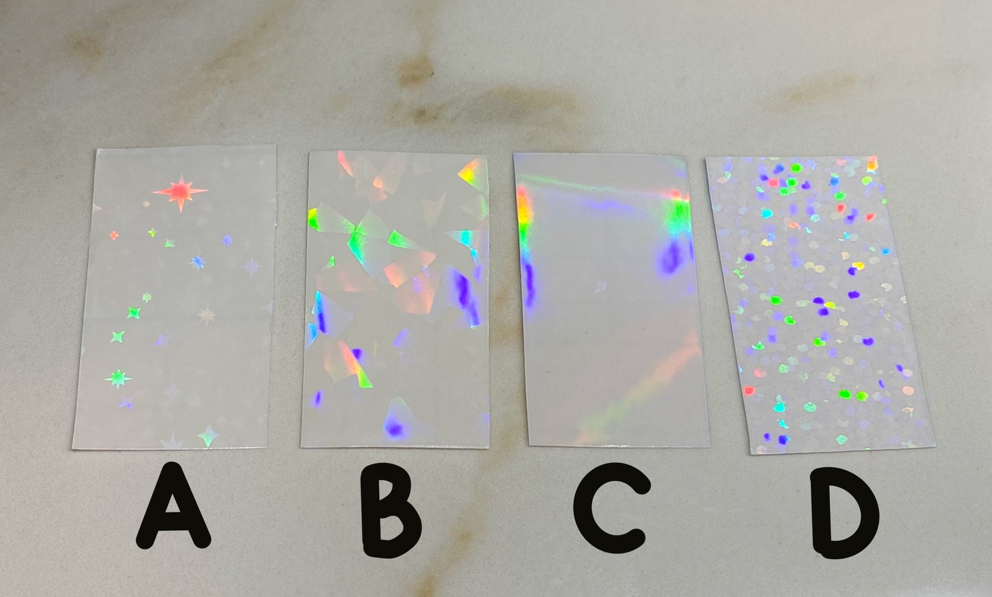 Four holographic paper samples labeled A, B, C, and D.