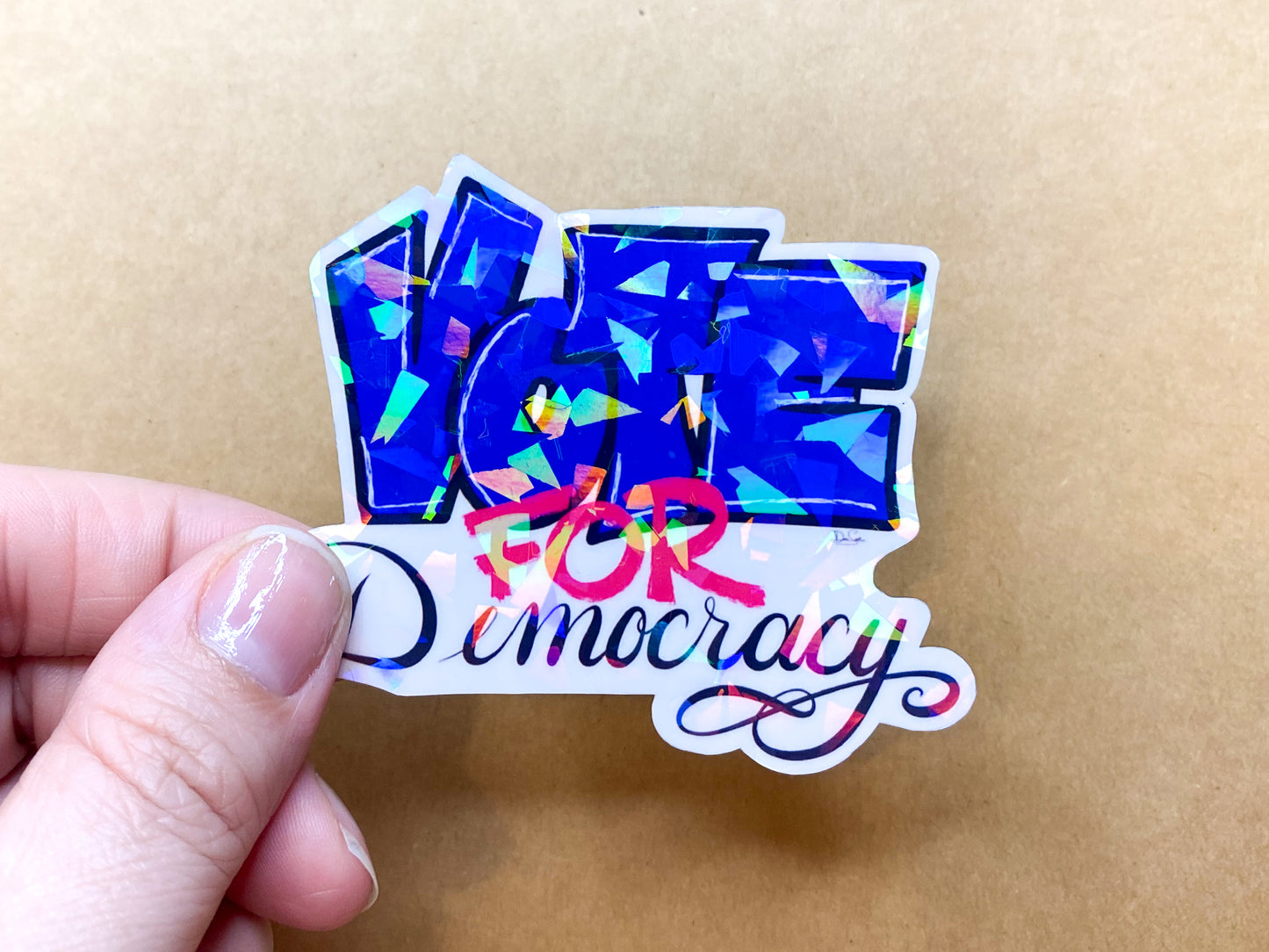 Vote for Democracy sticker held in hand for scale.