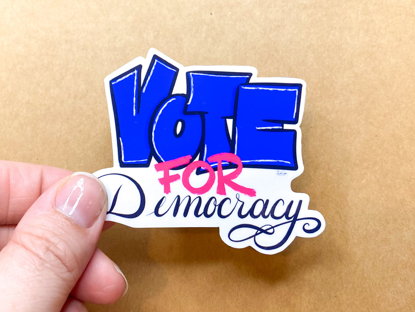 Vote for Democracy sticker held in hand for scale.