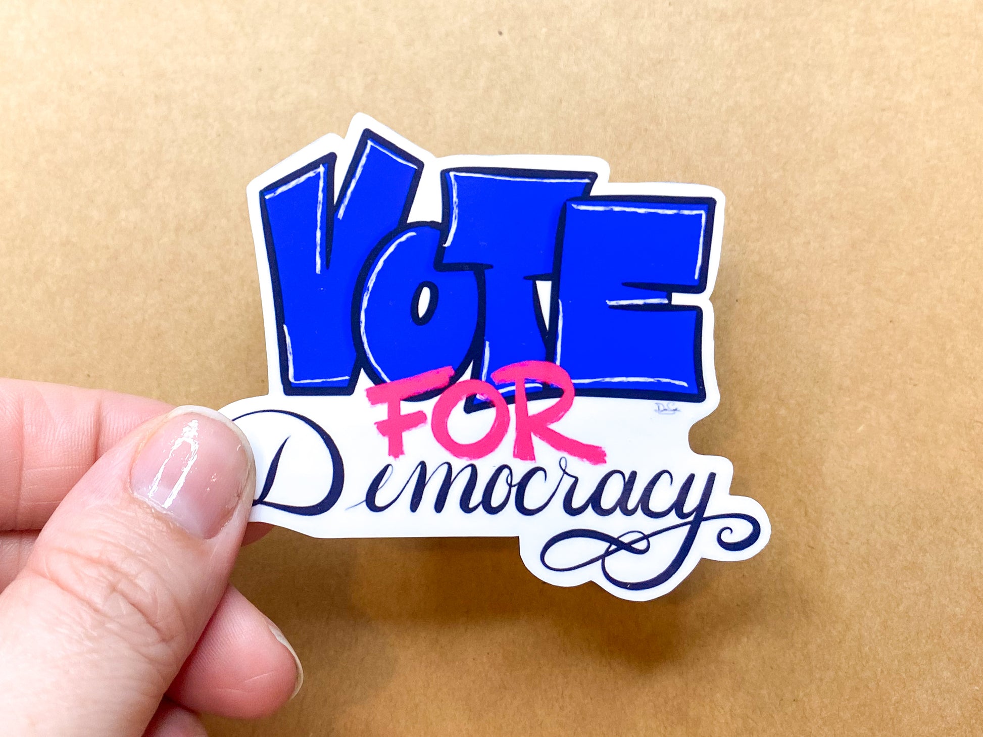 Vote for Democracy sticker held in hand for scale.