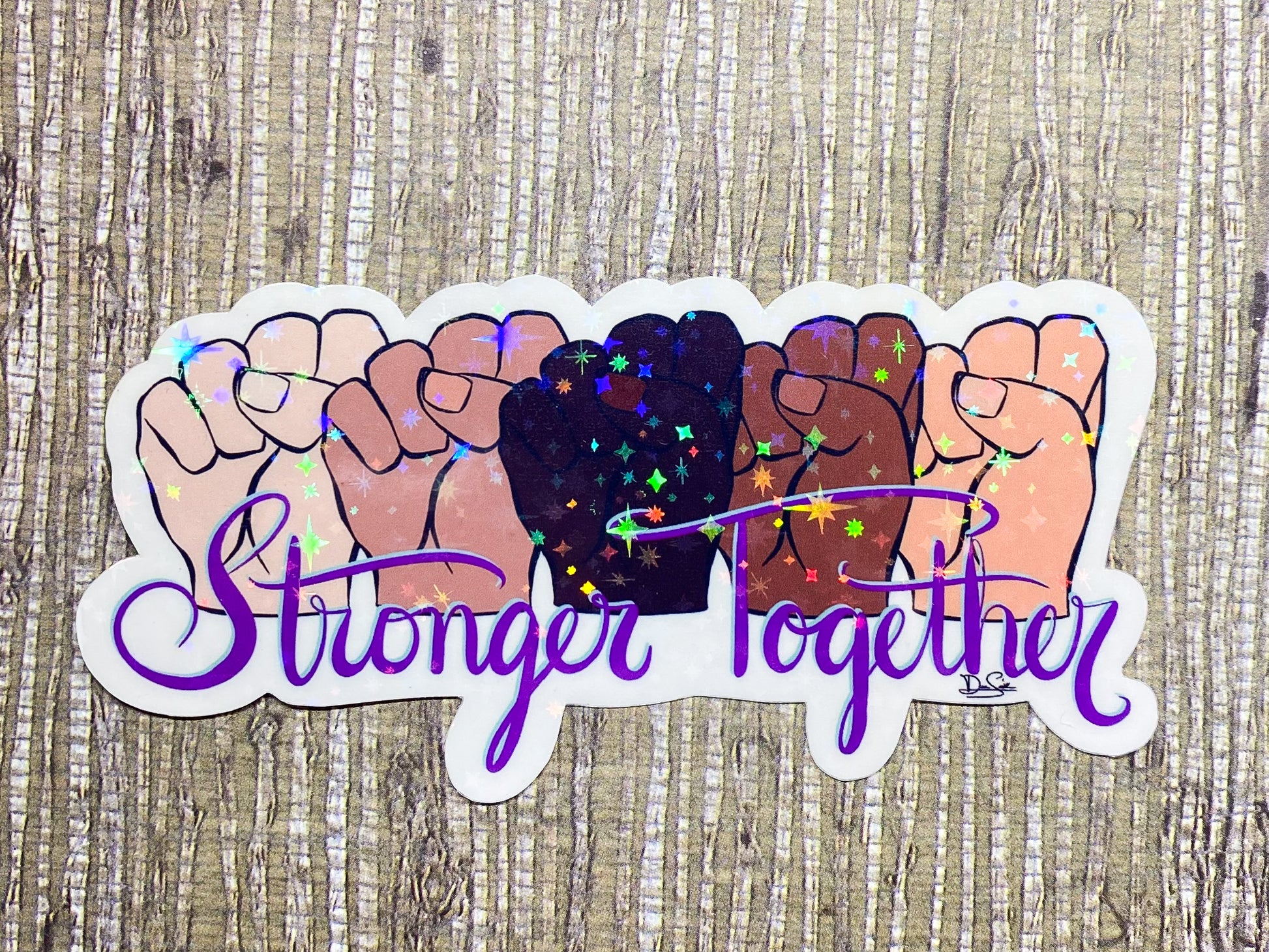 Image shows a sticker featuring five fists in various skin tones above the words Stronger Together in purple, cursive font 